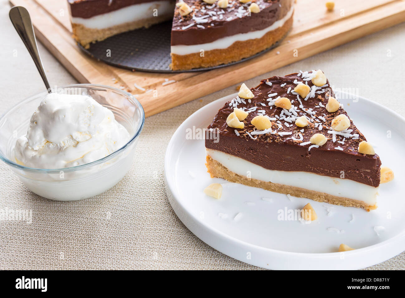 Haupia decadente e crema al cioccolato torta guarnita con radere noce di cocco, noci di macadamia e scaglie di cioccolato con panna montata Foto Stock