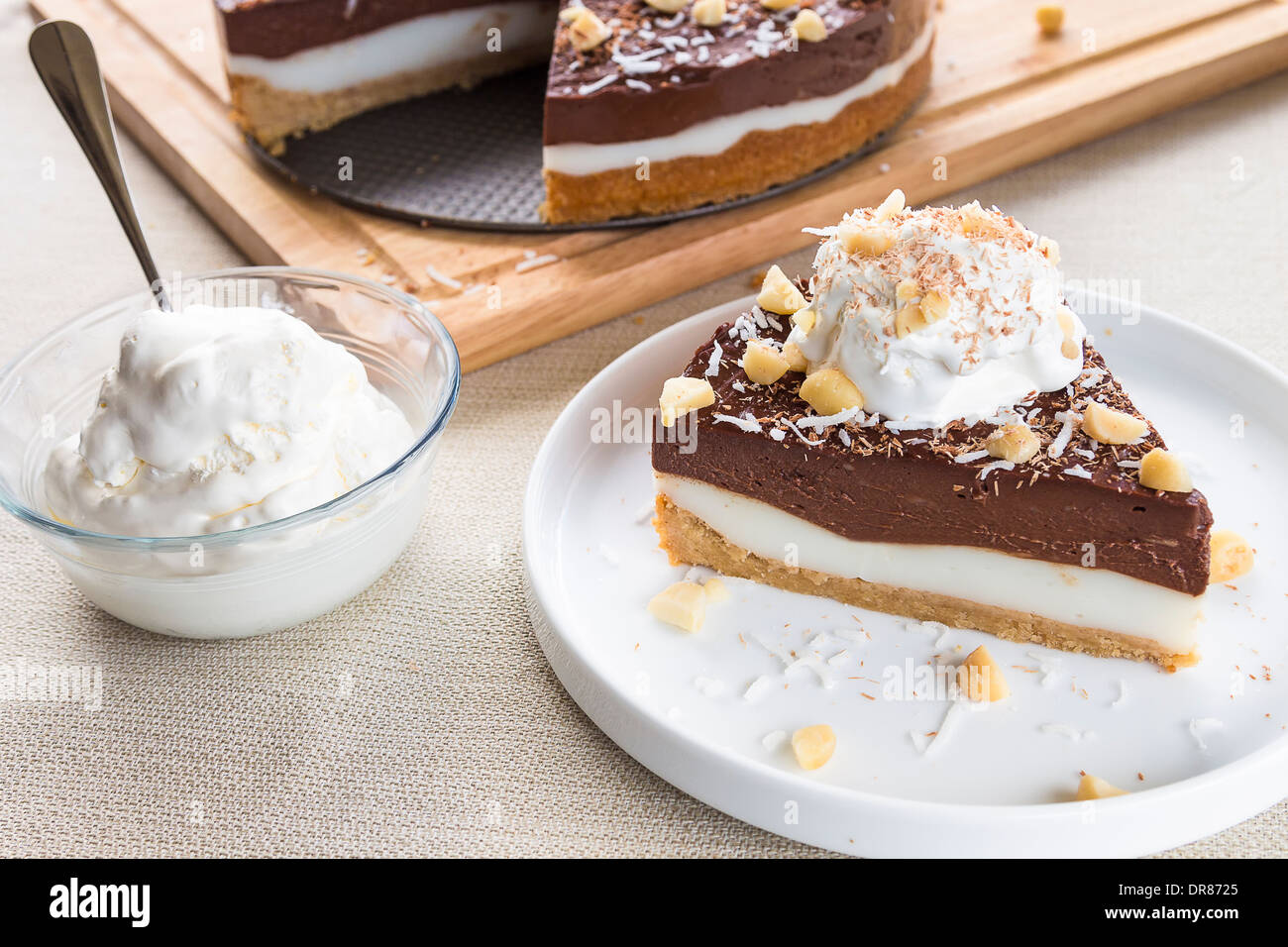 Haupia decadente e crema al cioccolato torta guarnita con radere noce di cocco, noci di macadamia e scaglie di cioccolato con panna montata Foto Stock