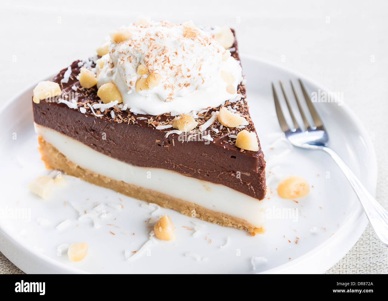 Haupia decadente e crema al cioccolato torta guarnita con radere noce di cocco, noci di macadamia e scaglie di cioccolato con panna montata Foto Stock