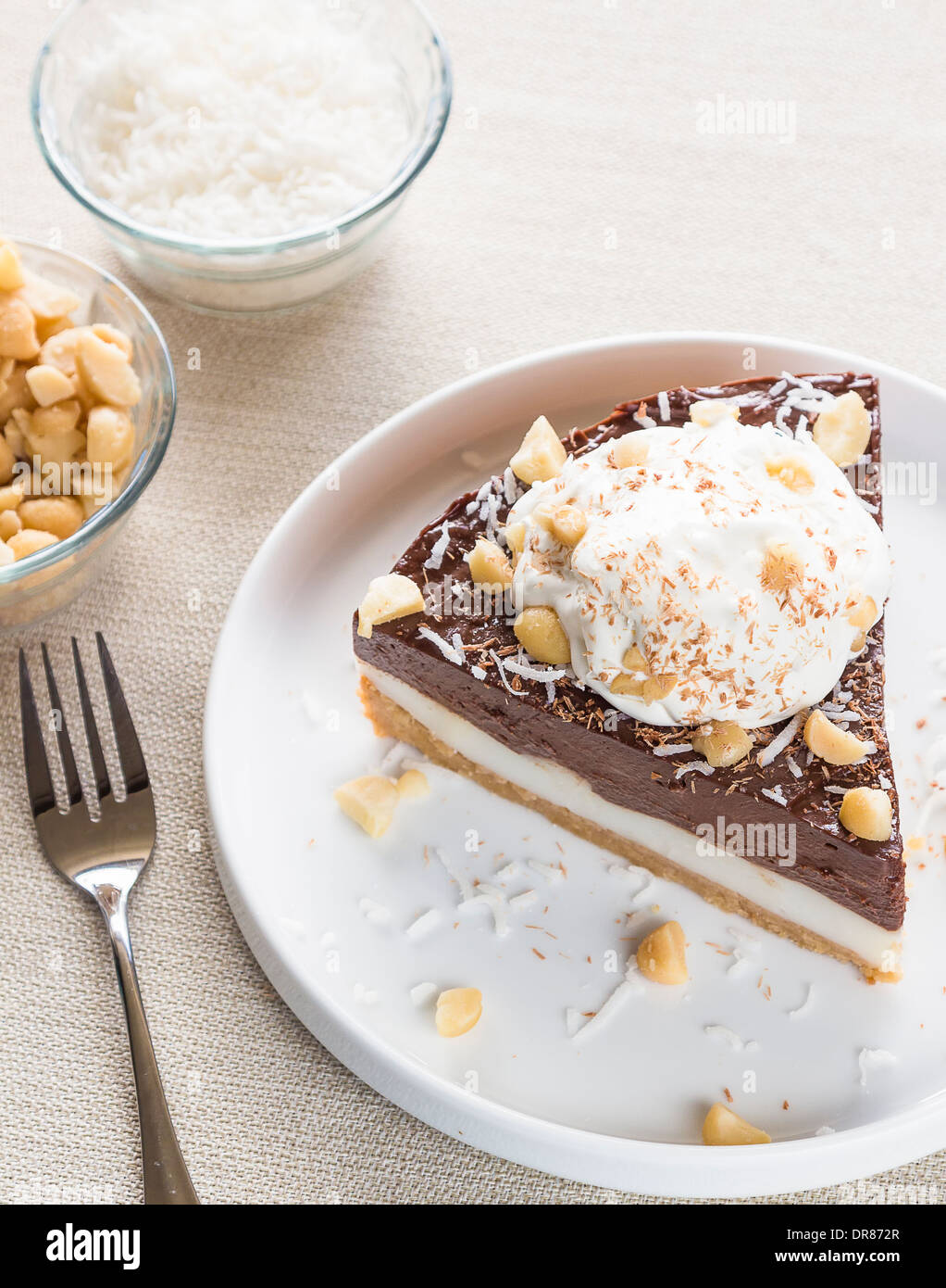 Haupia decadente e crema al cioccolato torta guarnita con radere noce di cocco, noci di macadamia e scaglie di cioccolato con panna montata Foto Stock