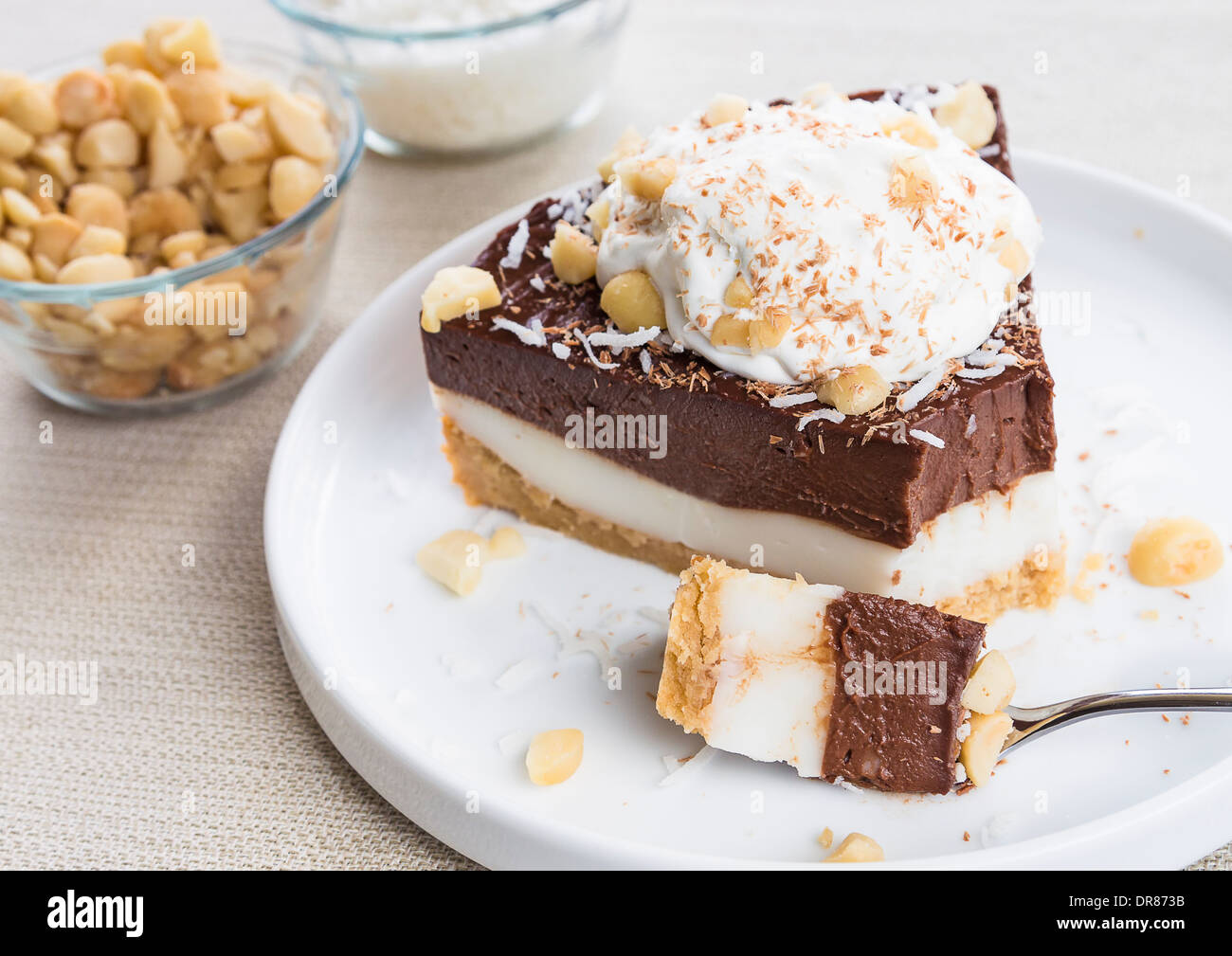 Haupia decadente e crema al cioccolato torta guarnita con radere noce di cocco, noci di macadamia e scaglie di cioccolato con panna montata Foto Stock