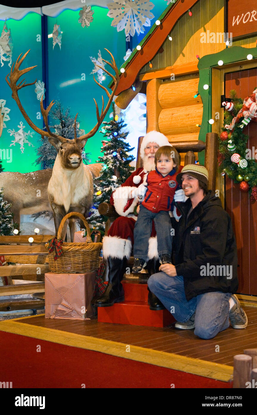 Ragazzo seduto su Babbo Natale in giro con il suo padre accanto a lui Foto Stock