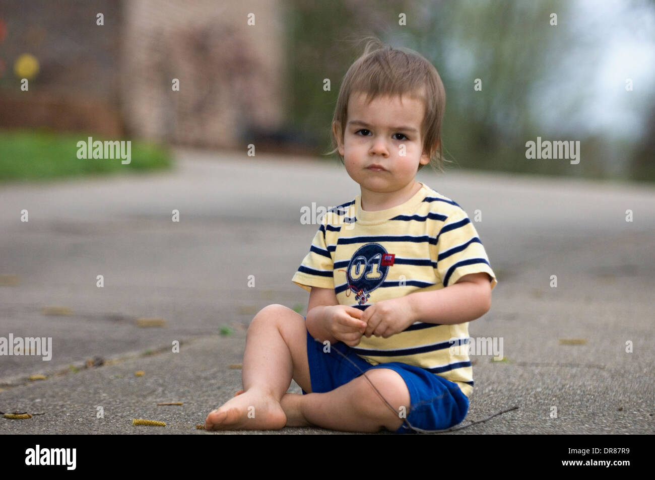 Bambino seduto sul cemento carraio giocando Foto Stock