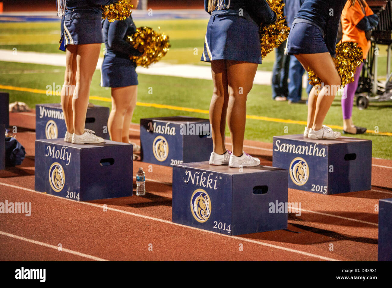 Cheerleaders stand su piattaforme personalizzate durante una notte di alta scuola di calcio a San Juan Capistrano, CA. Foto Stock