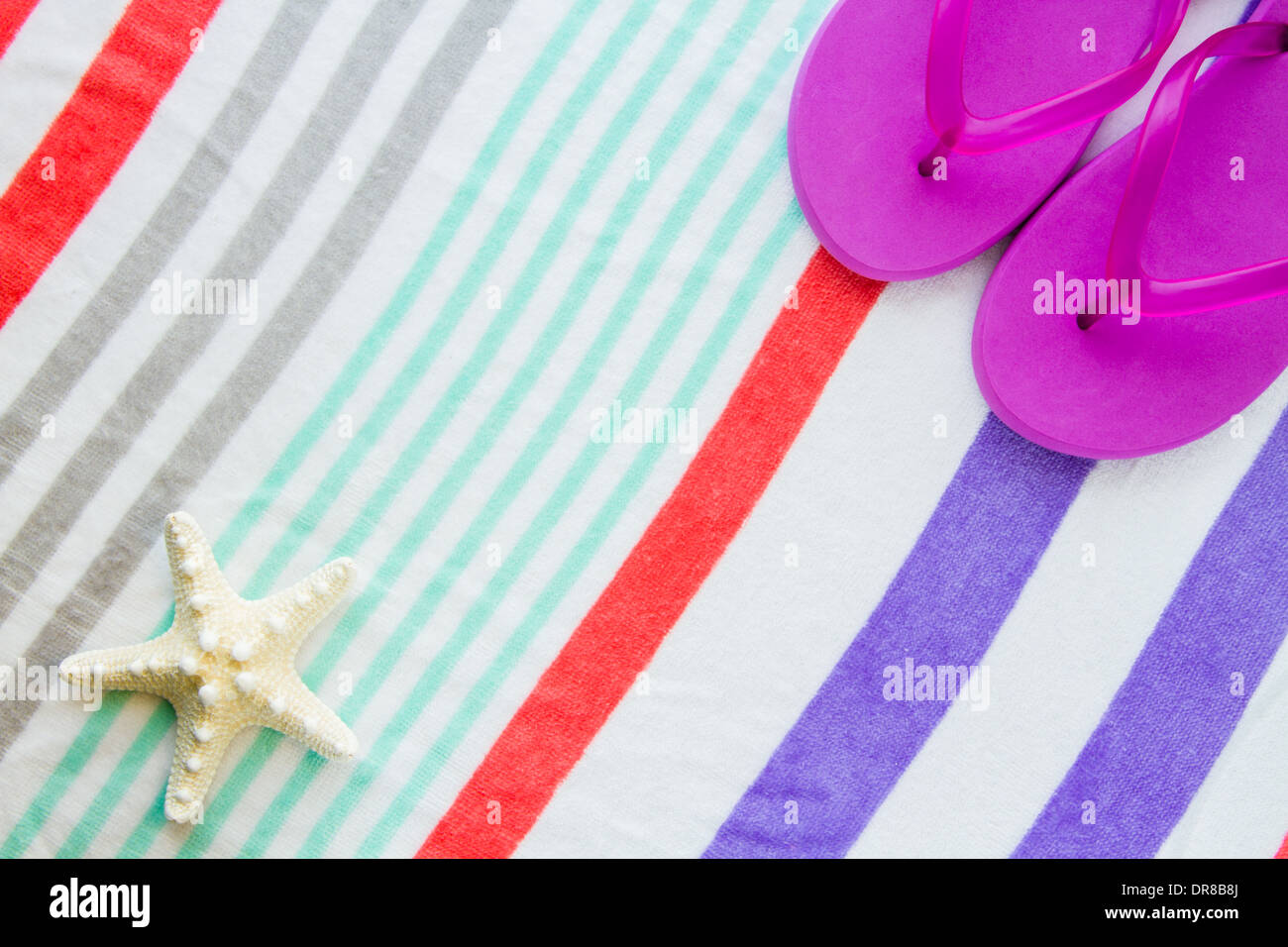 Spiaggia scena con viola infradito e una stella di mare su una spiaggia a strisce asciugamano. Foto Stock