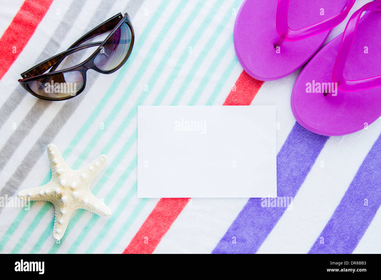 Spiaggia scena con viola infradito, una stella di mare e occhiali da sole su di una spiaggia a strisce asciugamano con copia spazio. Foto Stock