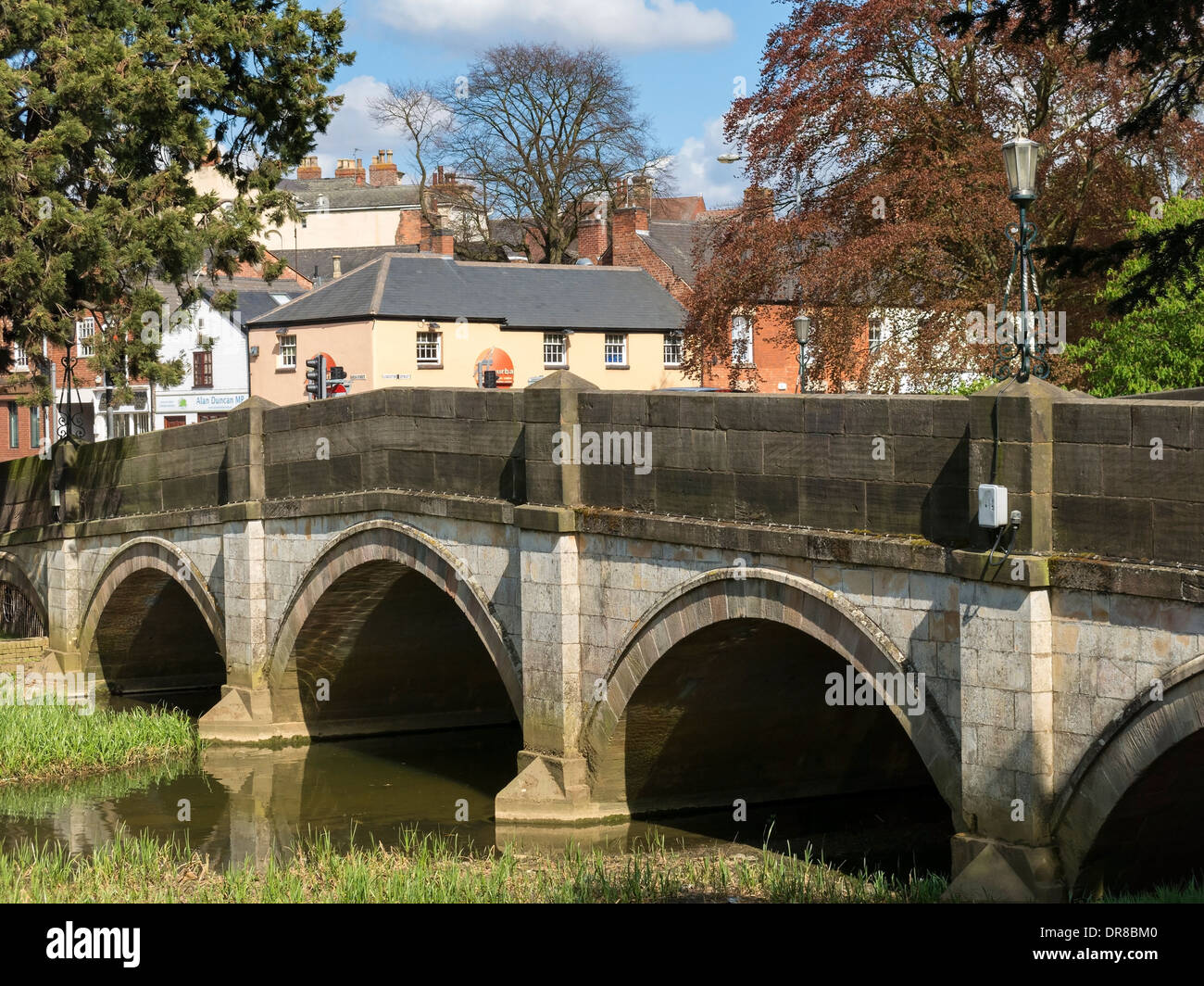 Gli archi in pietra di Lady Wilton Bridge, sopra il River Eye con gli edifici del centro città oltre, Melton Mowbray, Leicestershire, Inghilterra, Regno Unito. Foto Stock