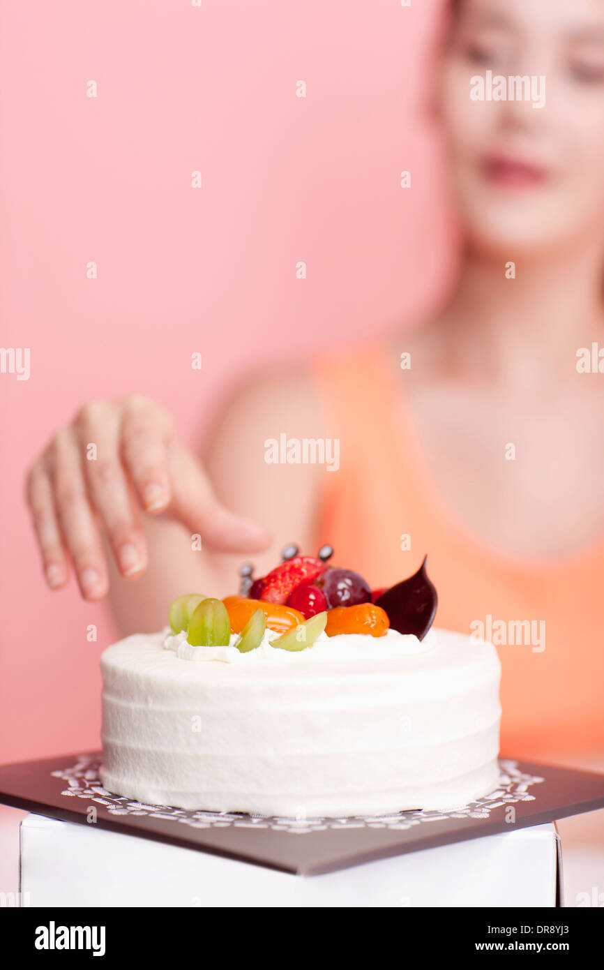 Una donna che sta per agguantare una torta di fronte a lei Foto Stock