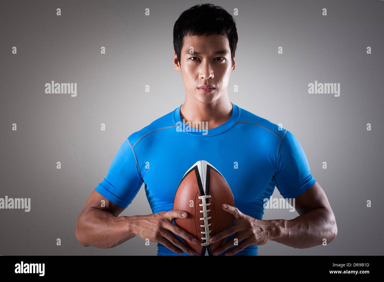 Montare un uomo in maglietta blu in posa con palla da rugby Foto Stock