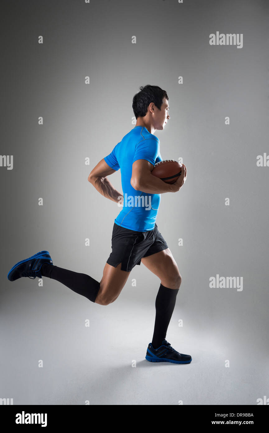 Montare un Uomo in camicia blu acceso con palla da rugby Foto Stock