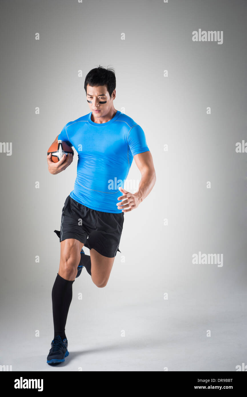 Montare un Uomo in camicia blu acceso con palla da rugby Foto Stock