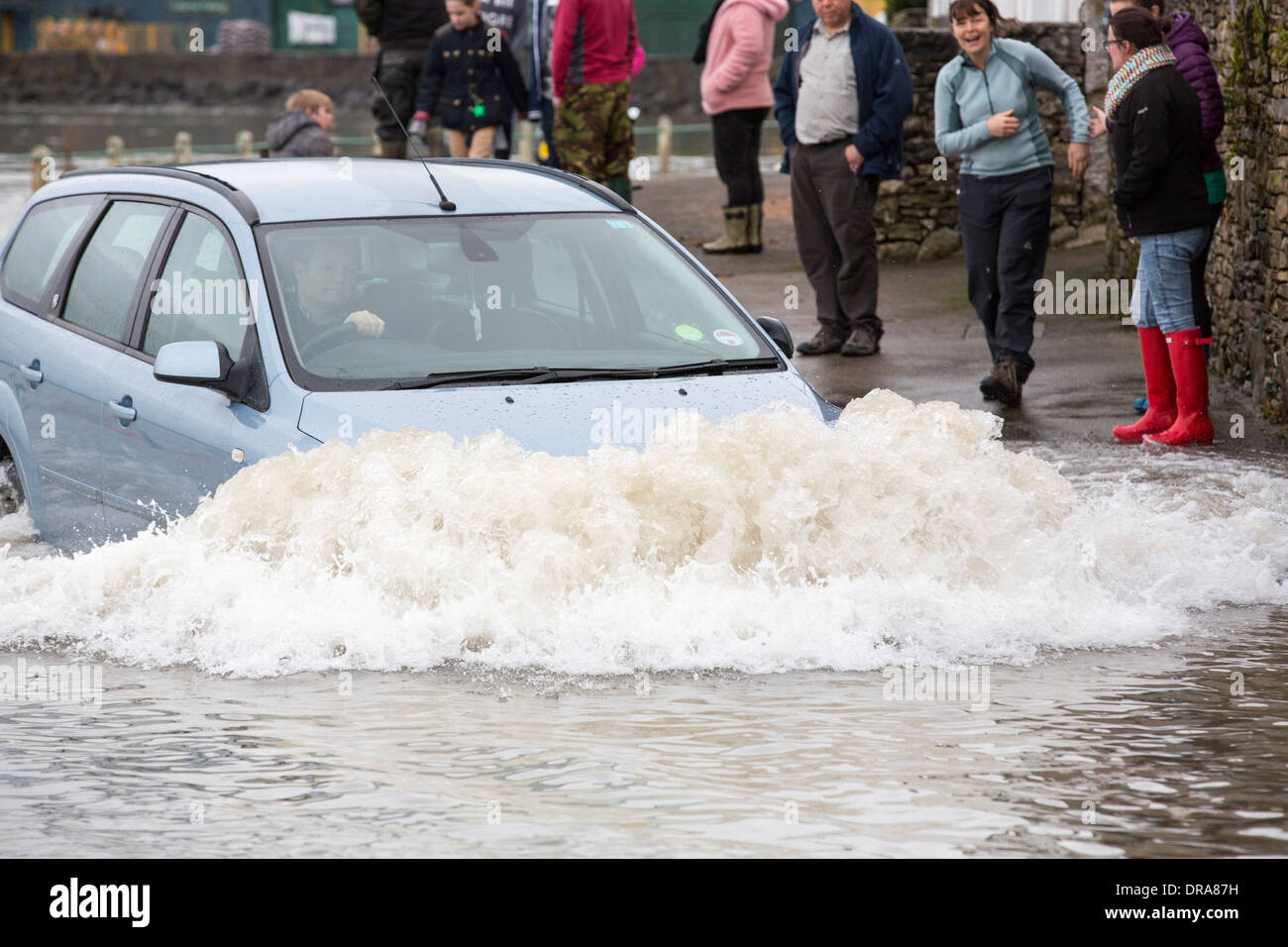 Un automobilista viaggia attraverso le acque di esondazione su strada a Storth sul Kent Estuary in Cumbria, Regno Unito, durante il mese di gennaio 2014 tempeste Foto Stock