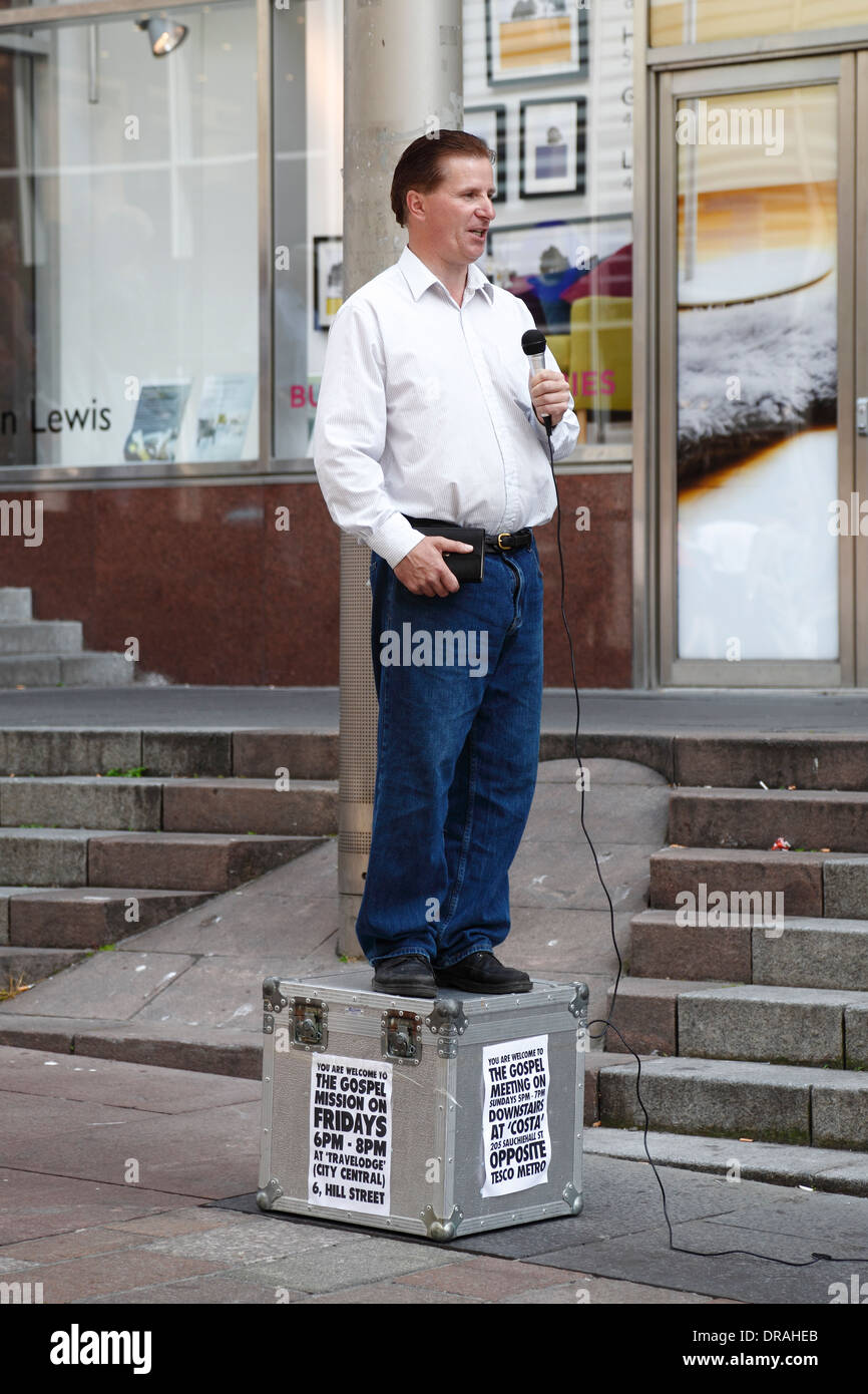 Un uomo in piedi su una scatola e usando un microfono per predicare il Vangelo su Buchanan Street, Glasgow centro città, Scozia, Regno Unito Foto Stock
