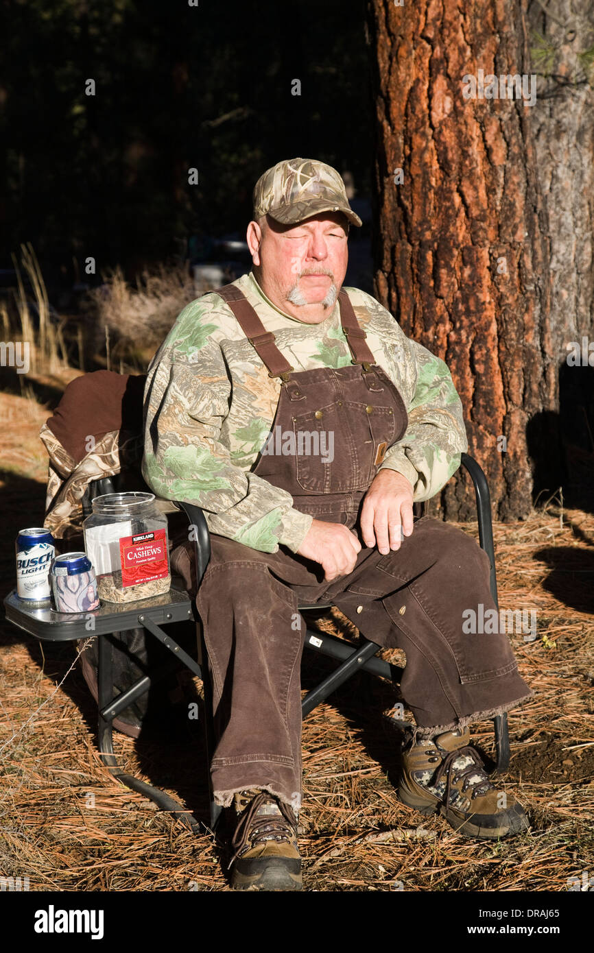 Un anziano uomo vestito con una tuta si siede su una sedia di camp vicino Metolius, Oregon Foto Stock
