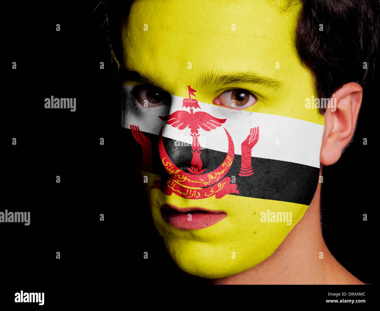 Bandiera del Brunei dipinta su una faccia di un giovane uomo Foto Stock