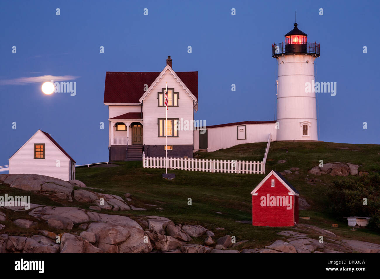La luna piena sorge al di sopra del Capo Faro Neddick noto anche come Nubble luce in York Beach, Maine. Foto Stock