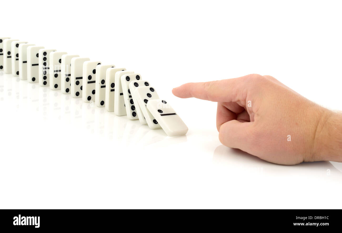 Concetto di avviare un processo o reazione a catena di eventi, un dito spingendo un domino isolato su uno sfondo bianco Foto Stock