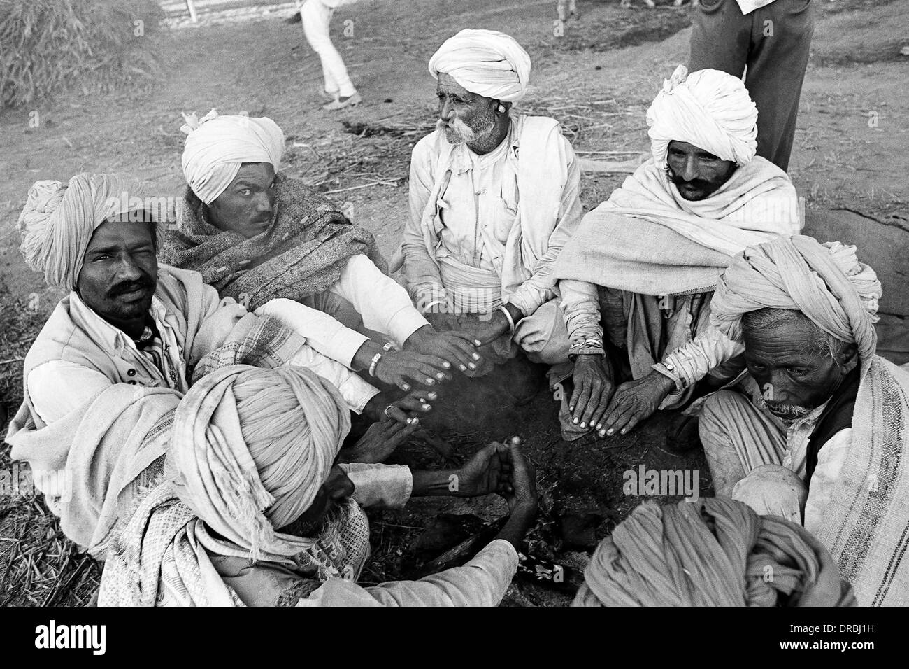 Sette uomini mani di riscaldamento in inverno freddo, Vautha fair, Gujarat, India, 1983 Foto Stock