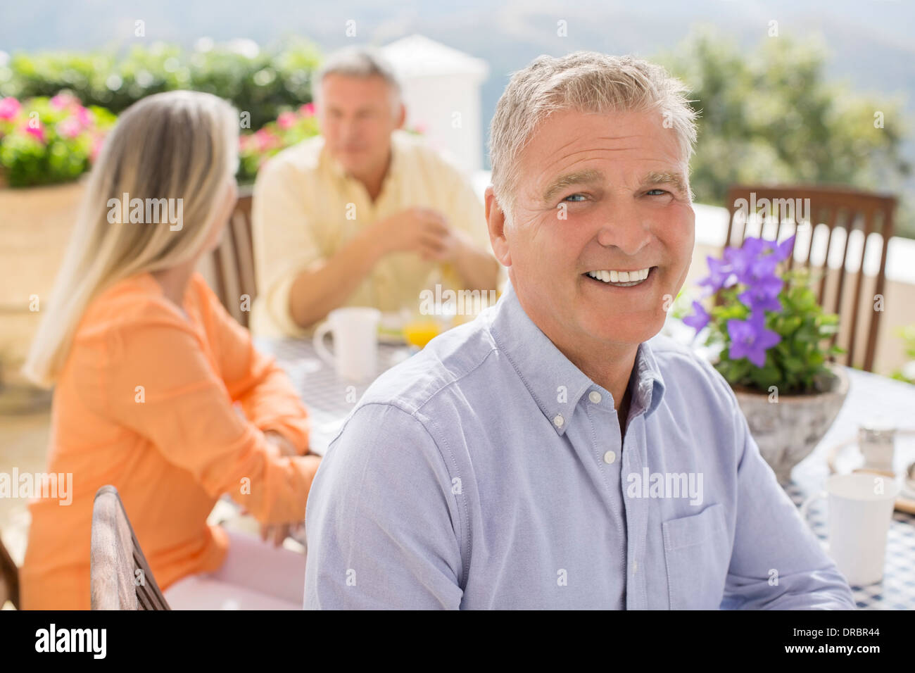 Senior uomo sorridente al patio tabella Foto Stock