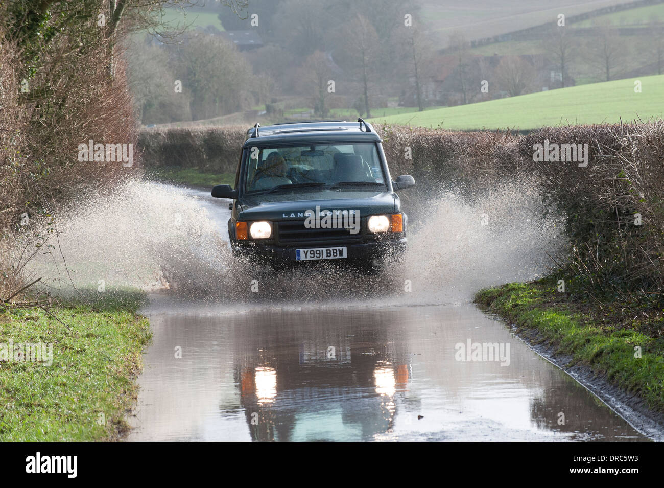 Land Rover Discovery 4x4 di guida attraverso le acque di esondazione su un vicolo del paese, Hampshire, Regno Unito Foto Stock