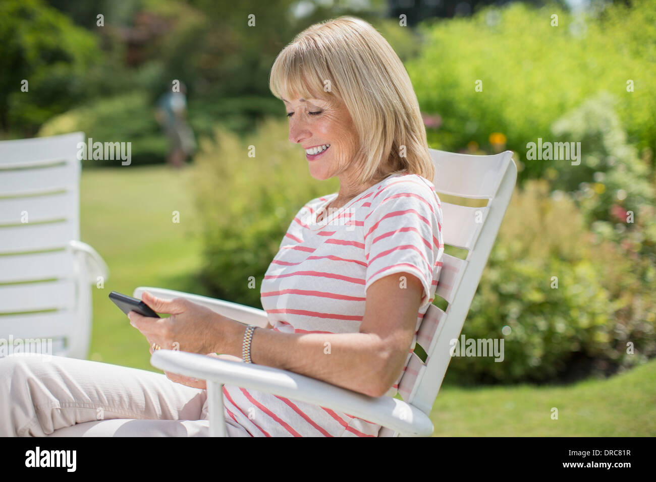 Donna che utilizza il cellulare in giardino Foto Stock