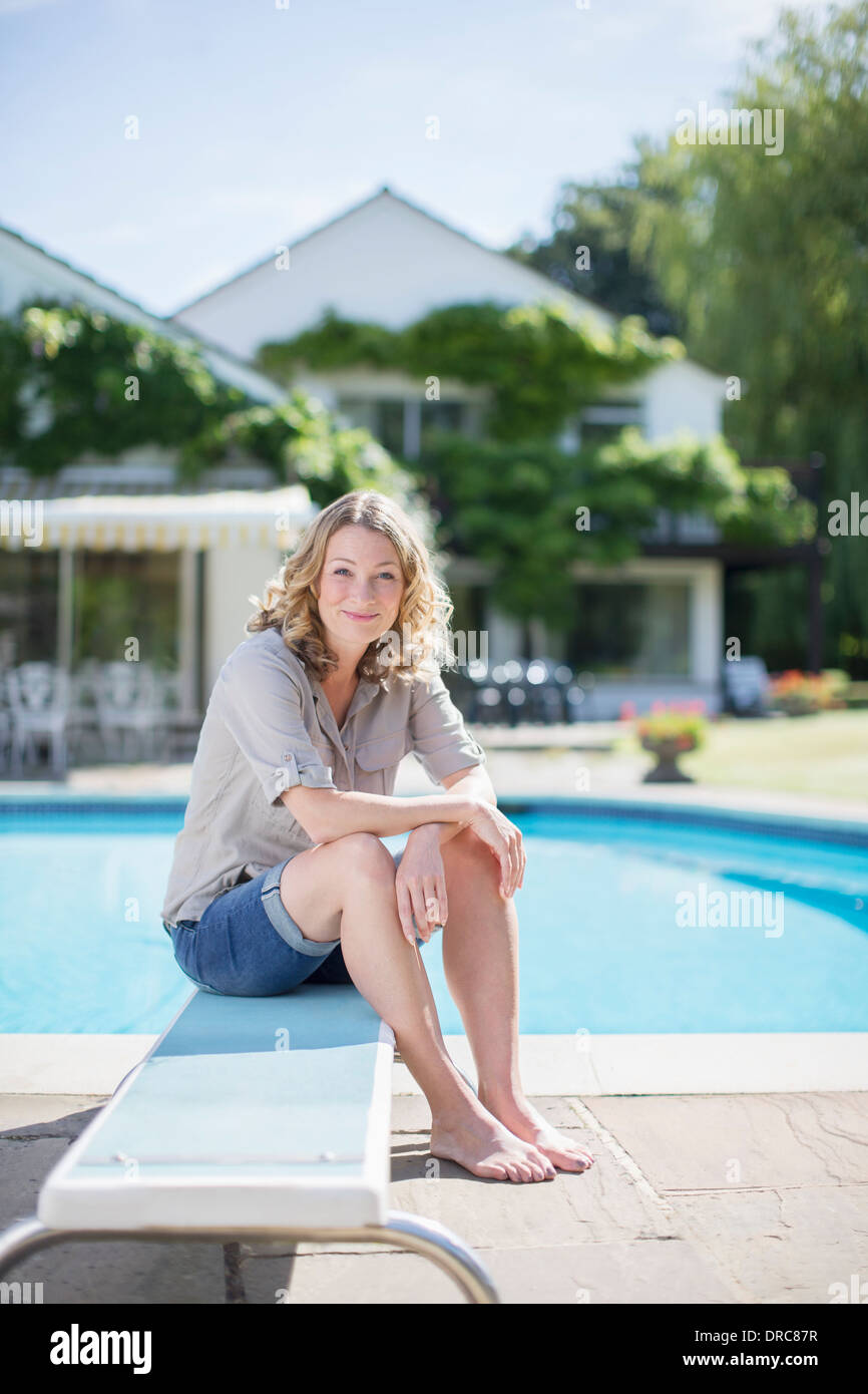 Donna seduta sulla scheda di immersioni presso la piscina Foto Stock