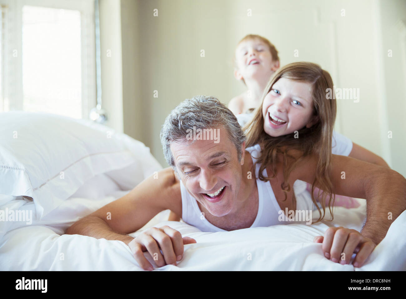 Padre e figli giocare sul letto Foto Stock