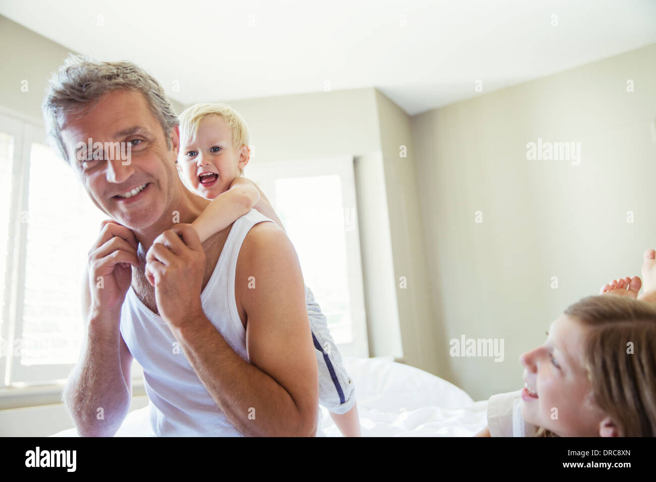 Padre e figli giocare sul letto Foto Stock