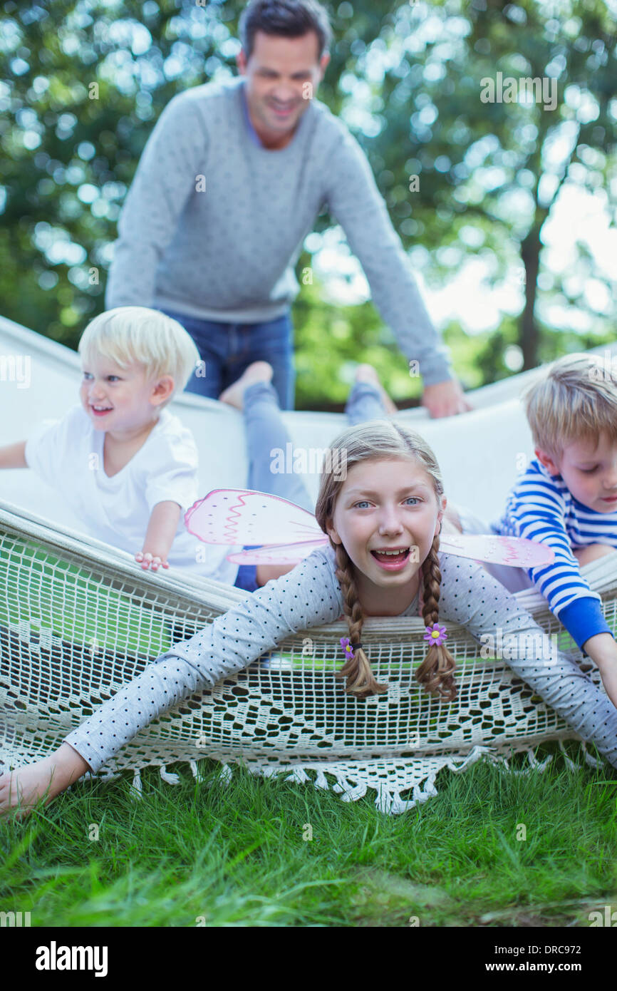 Padre spingendo i bambini in amaca all'aperto Foto Stock