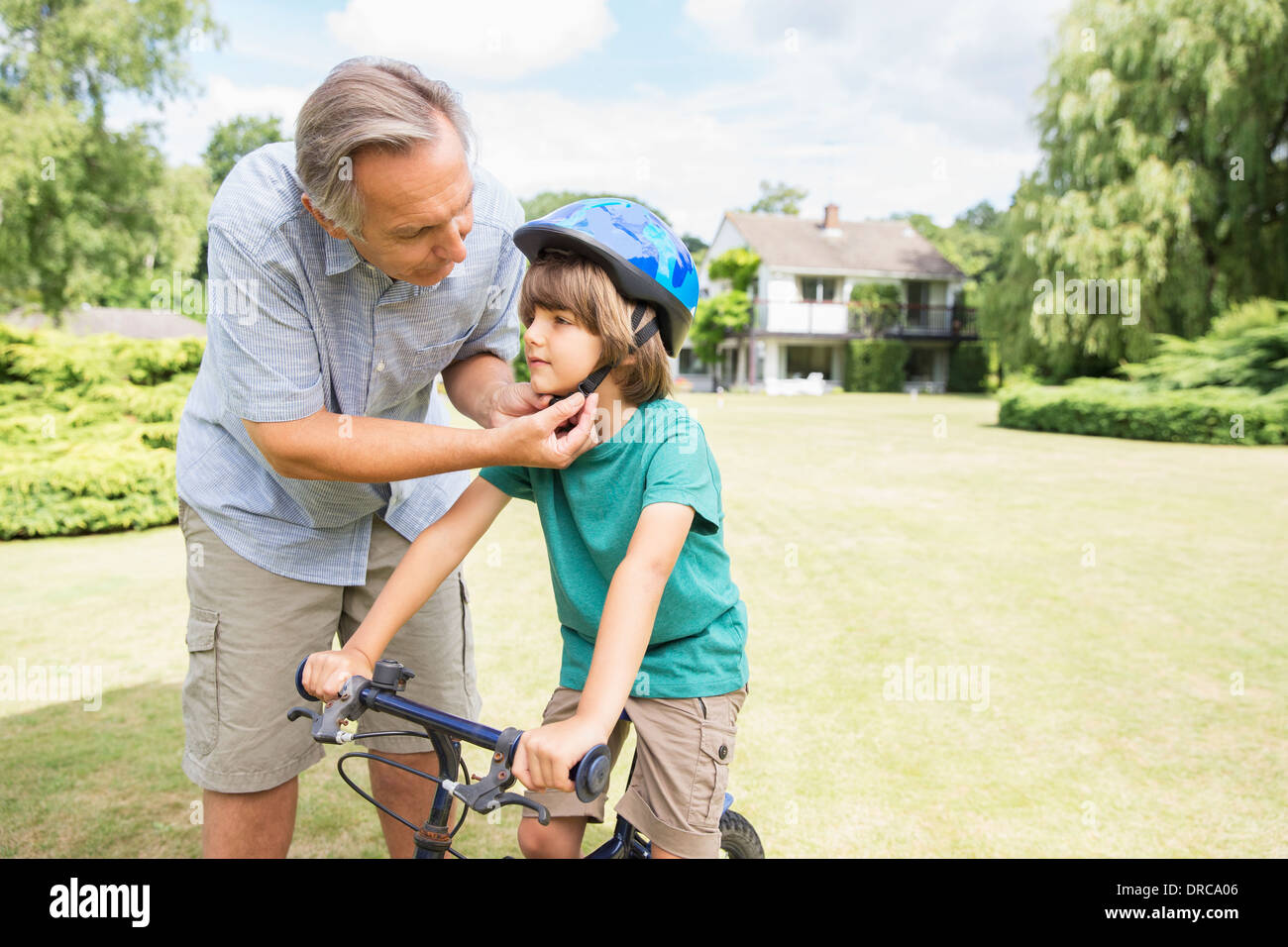 Regolazione del nonno noleggio casco su nipote Foto Stock Regolazione del nonno noleggio casco su nipote Foto Stock
