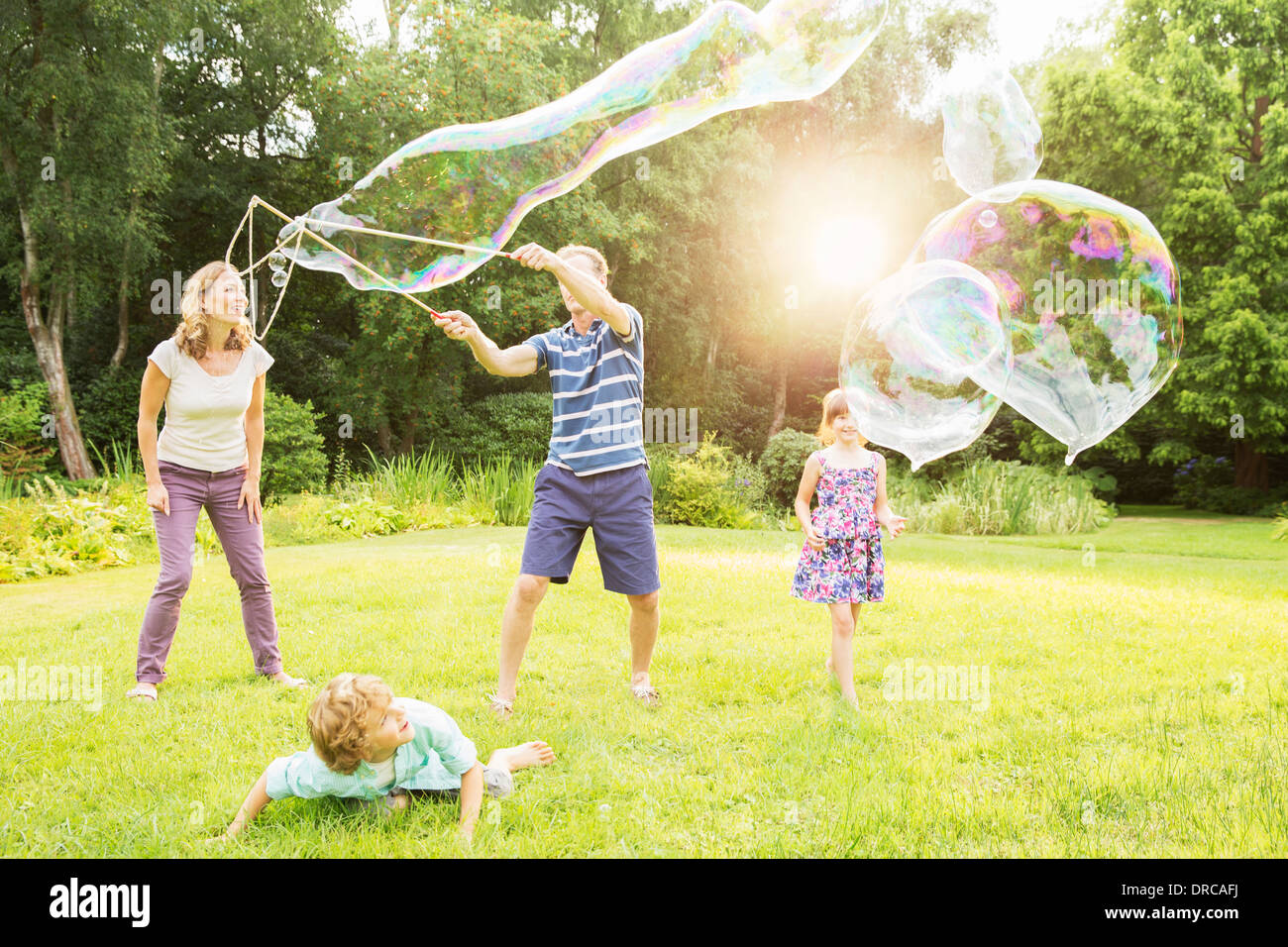 La famiglia gioca con bolle grandi nel cortile posteriore Foto Stock