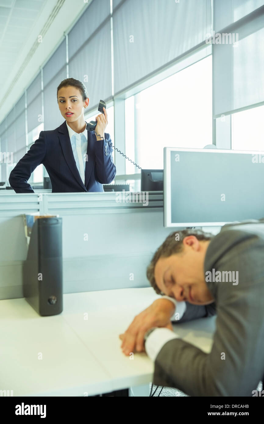Imprenditrice guardando dormire imprenditore in office Foto Stock