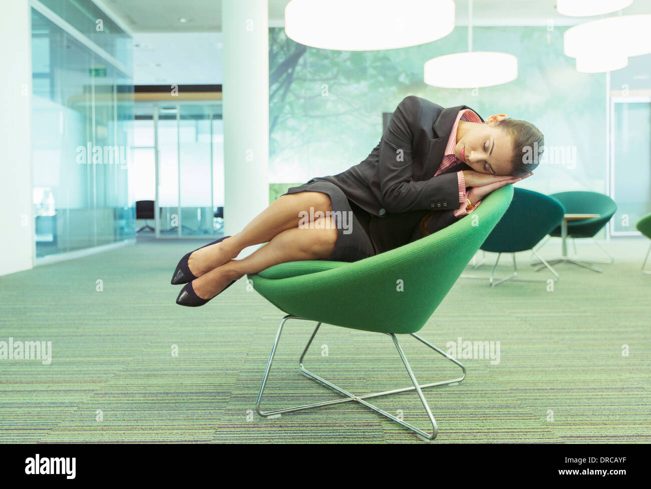 Imprenditrice napping in sedia ufficio Foto Stock
