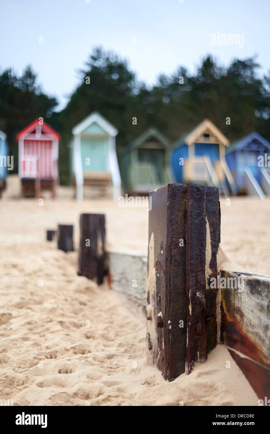 Groyne difesa del mare con la pittoresca spiaggia di capanne a Wells accanto al mare, North Norfolk, Inghilterra, Regno Unito Foto Stock