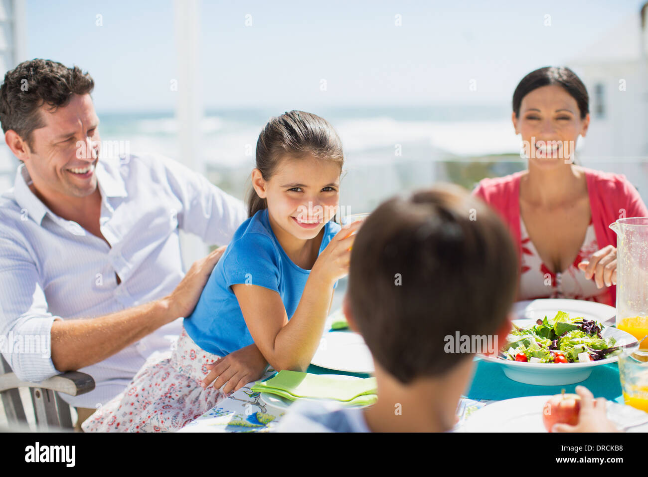 Famiglia di mangiare il pranzo al tavolo sul patio soleggiato Foto Stock