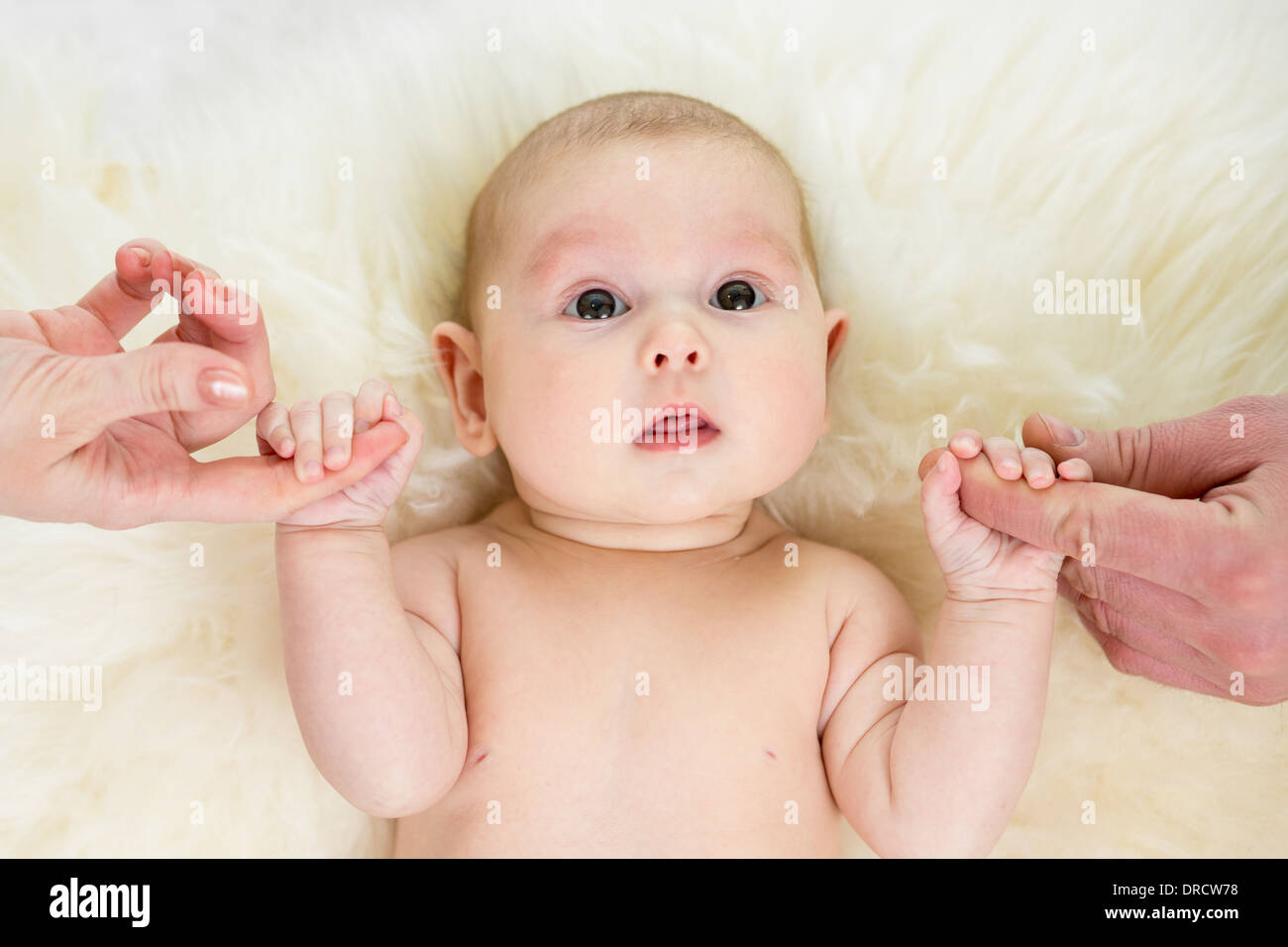 Baby girl tenendo le mani dei genitori Foto Stock