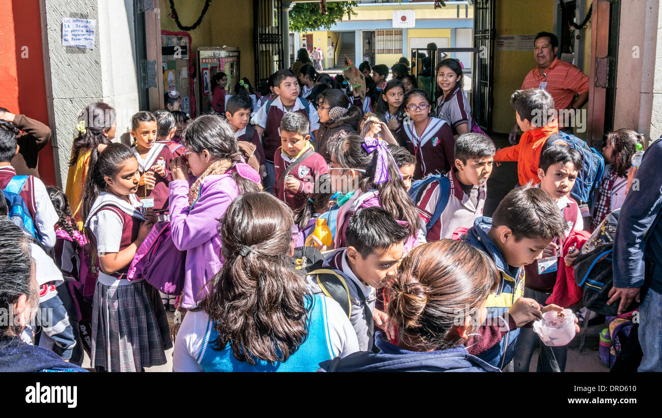 Gli insegnanti supervisionare esuberante folla di felice ragazze e ragazzi usciti su marciapiede dalla scuola primaria generale Vicente Guerrero Foto Stock