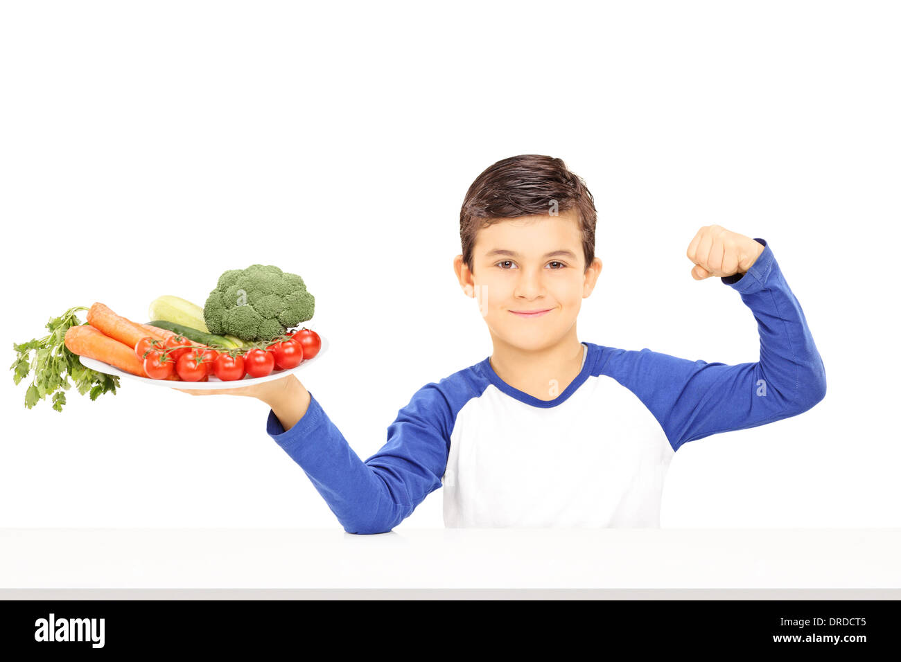 Ragazzo giovane tenendo la piastra piena di verdure e mostrando il muscolo Foto Stock