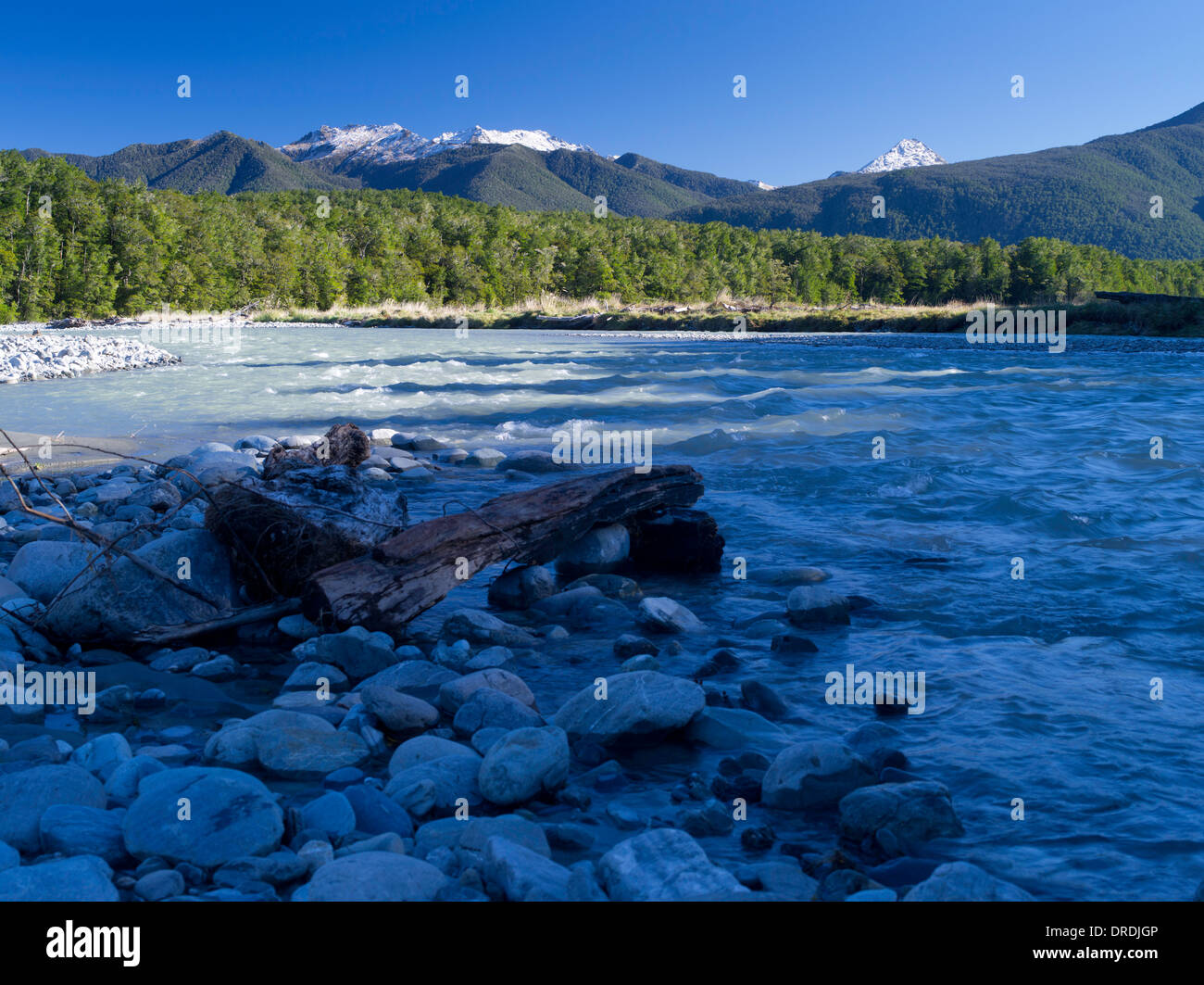 A basso angolo di vista del fiume Maruia e ciottoli, con la gamma di Victoria in background; Canterbury, Nuova Zelanda; Giugno 2013 Foto Stock