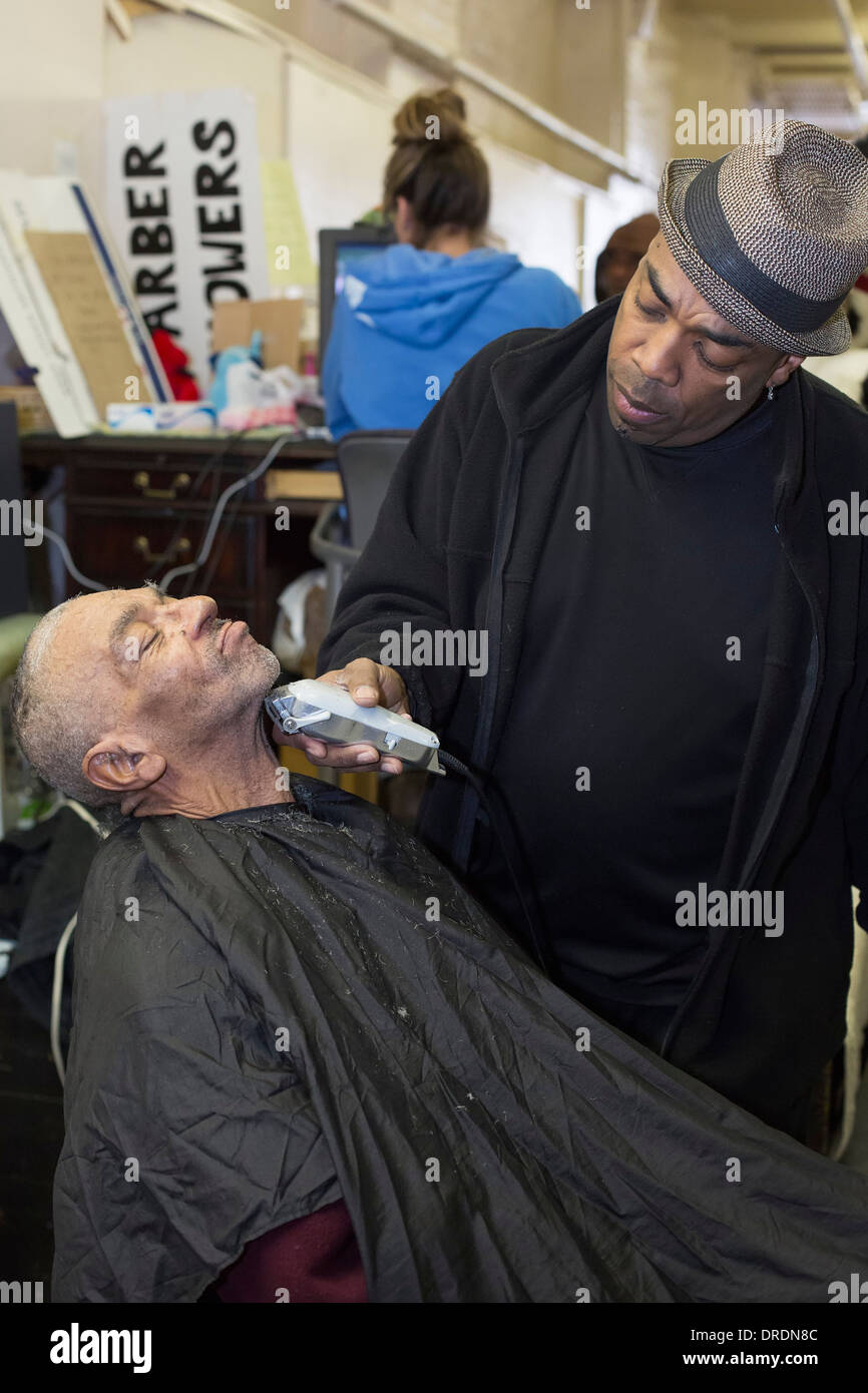 Detroit, Michigan - Barbiere Elvis Tucker dà un taglio di capelli e la barba di un uomo senza tetto Foto Stock
