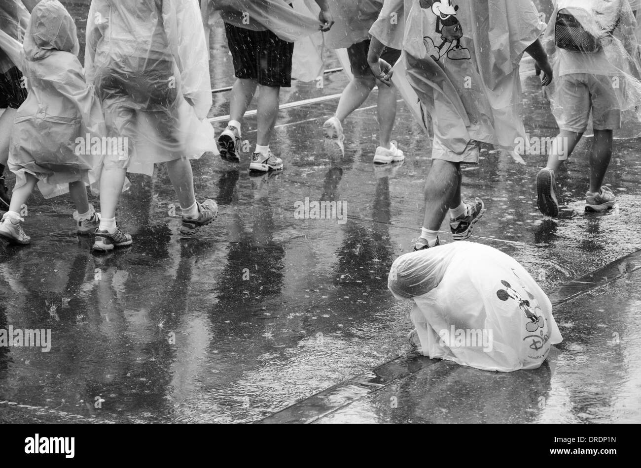 Un deluso bambino avvolto in un poncho con il Magic Kingdom parata è stata annullata a causa della pioggia in Walt Disney World, a Orlando Foto Stock