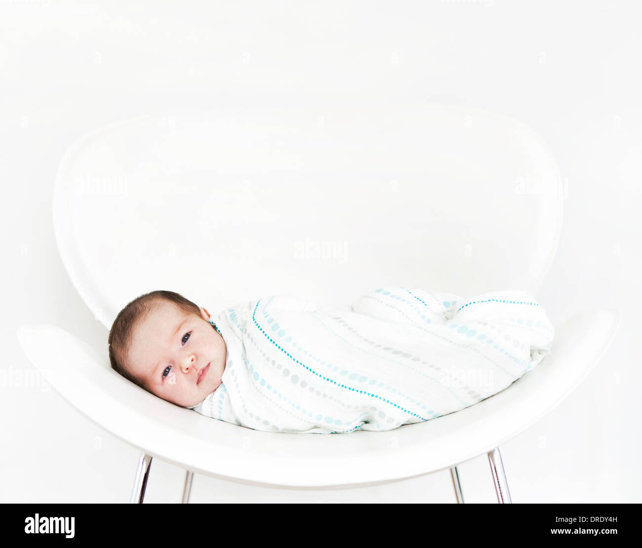 Swaddled baby sulla sedia bianca Foto Stock