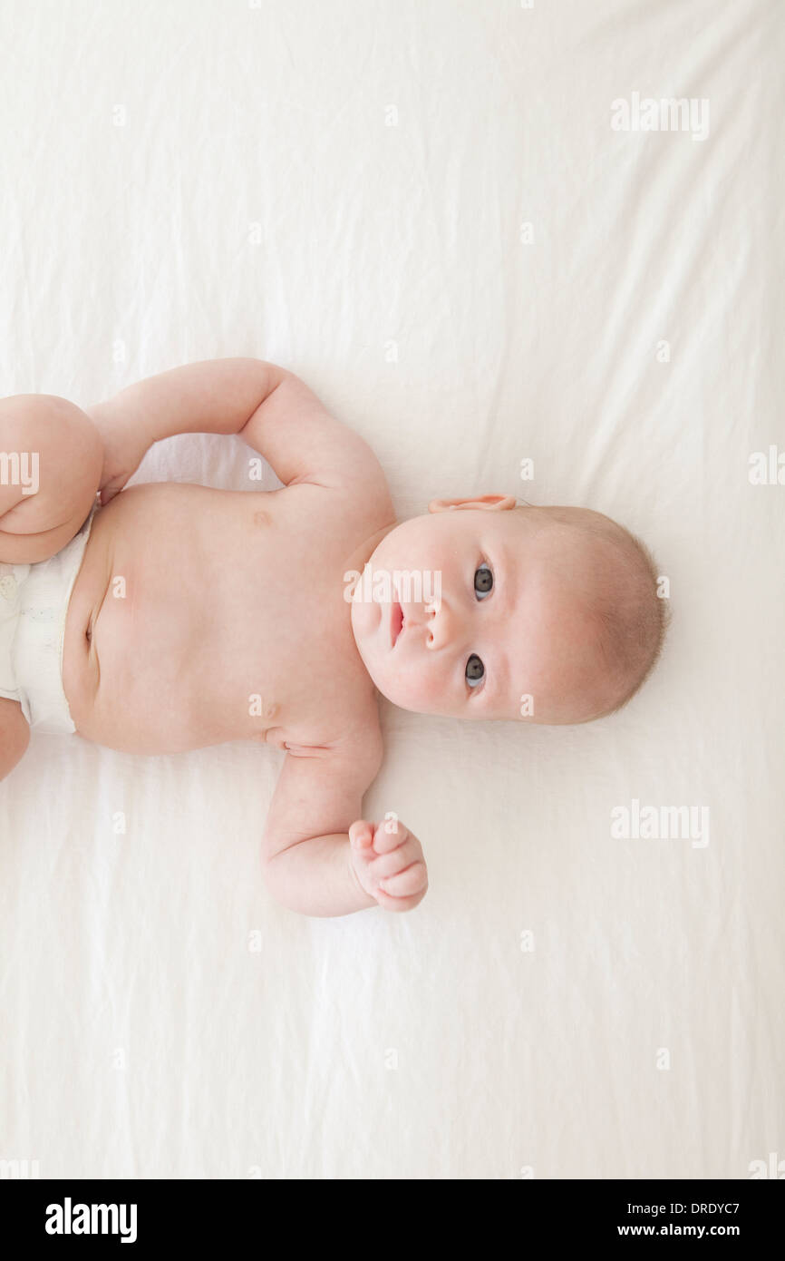 Baby nel pannolino giacente sul letto Foto Stock