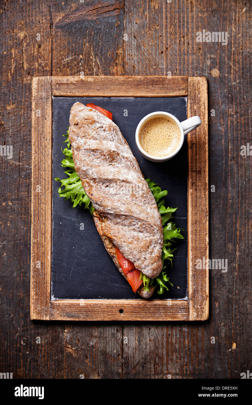 Sandwich con salmone affumicato e caffè su ardesia vintage chalk sfondo della scheda Foto Stock