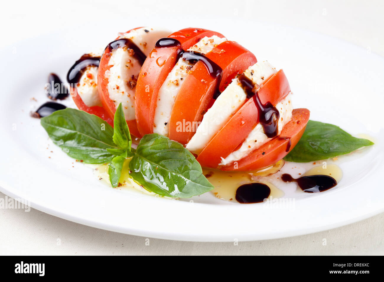Insalata caprese con pomodoro e fettine di mozzarella con foglie di basilico su sfondo bianco Foto Stock