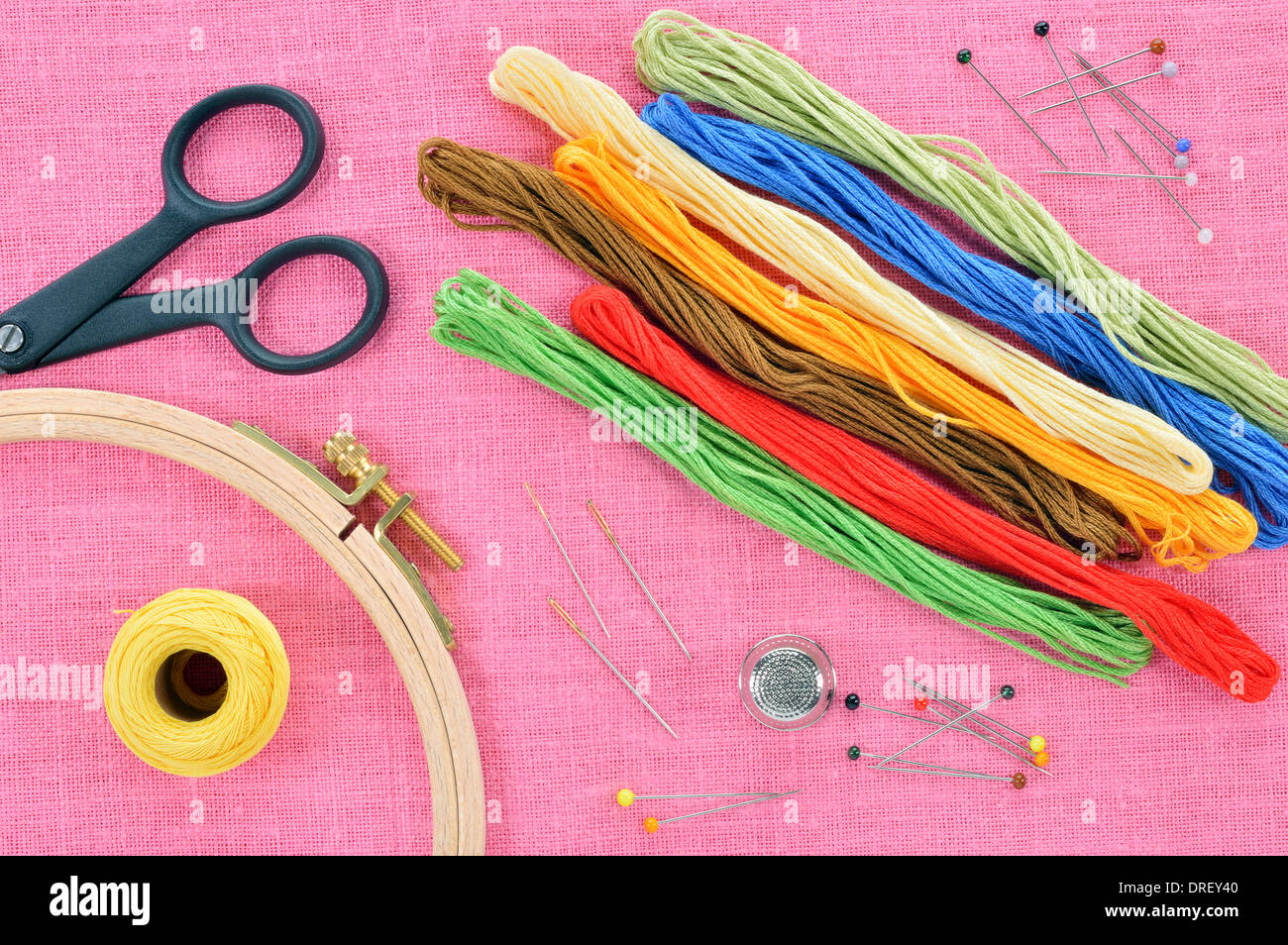 Ricamo e punto croce accessori rosa su tessuto di lino. Cerchio da ricamo, forbici, filo, aghi, ditale. Copia dello spazio. Foto Stock