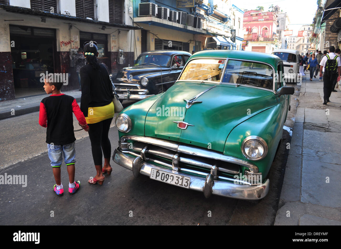 L'Avana, Cuba: scene di strada nel centro di Havana come persone di attraversare la strada tra classica vecchia auto americane. Foto Stock