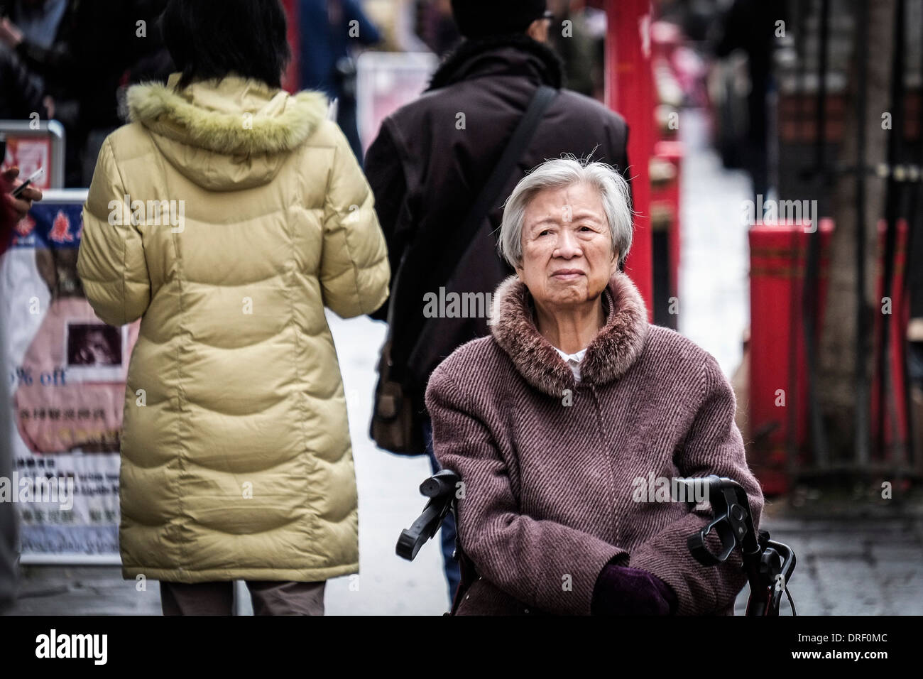 Un anziana signora cinese seduta in strada a Chinatown a Londra. Foto Stock