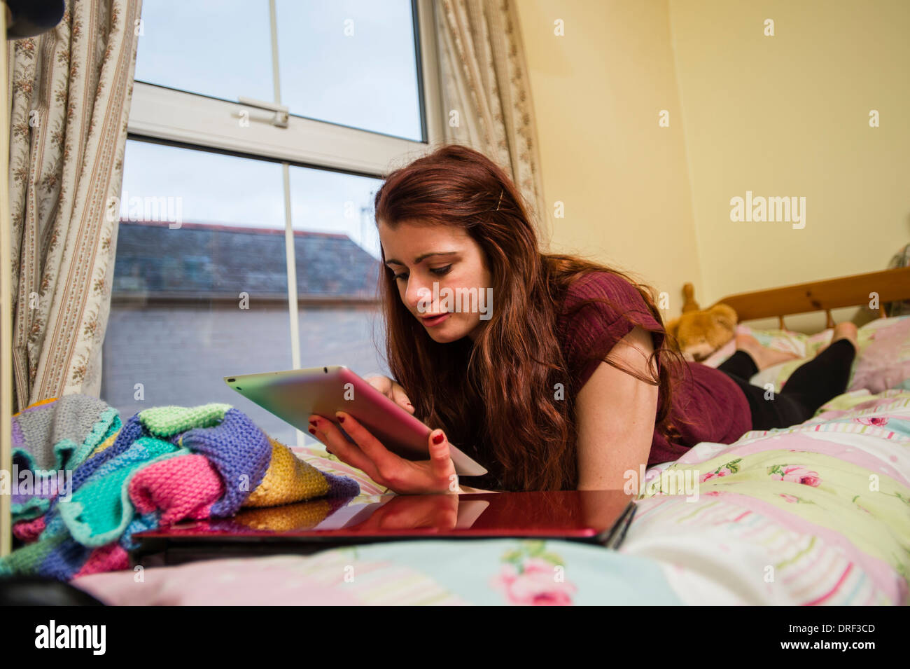 Un giovane studente universitario giacente sul letto studiare lavorare sul  suo iPad nella sua camera da letto a casa REGNO UNITO Foto stock - Alamy