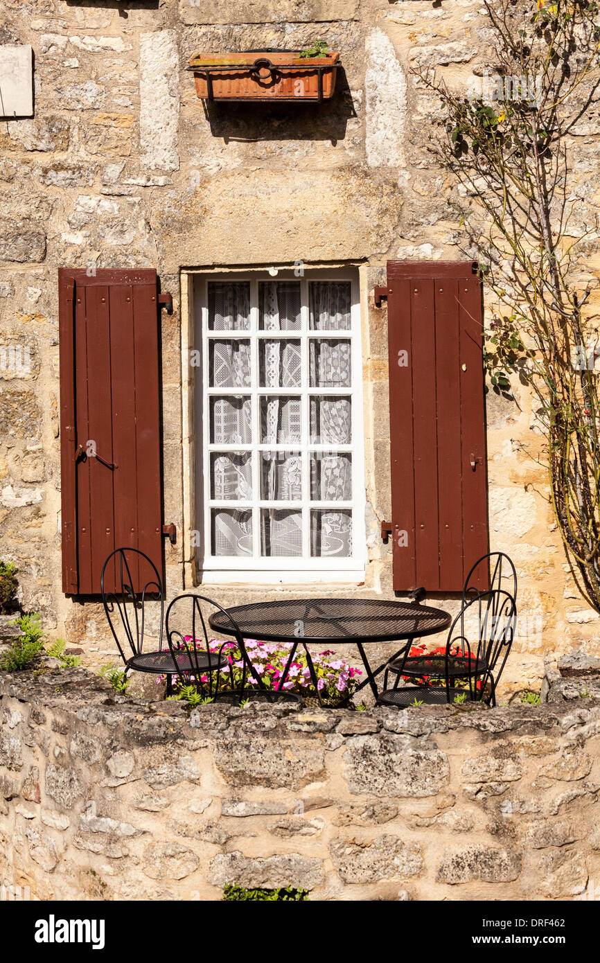 Beynac-et-Cazenac, Dordogne, la Francia, l'Europa. Tavolo e sedie da giardino esterno in pietra bellissima casa costruita e finestra ritagliata. Foto Stock